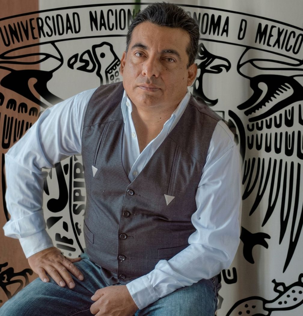 El Ing. Israel Villanueva frente al mural del escudo de la Universidad Nacional Autónoma de México